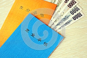 Japanese pension insurance booklets on table with yen money bills. Blue and orange books