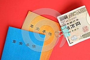 Japanese pension insurance booklets on table with yen money bills. Blue and orange books