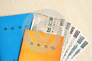 Japanese pension insurance booklets on table with yen money bills. Blue and orange books