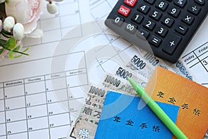 Japanese pension insurance booklets on table with yen money bills and calculator on table