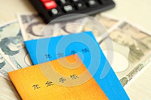 Japanese pension insurance booklets on table with yen money bills and calculator on table