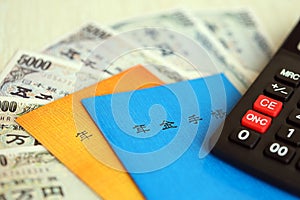 Japanese pension insurance booklets on table with yen money bills and calculator on table