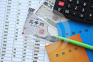 Japanese pension insurance booklets on table with yen money bills and calculator on table