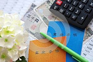 Japanese pension insurance booklets on table with yen money bills, pen and calculator on table