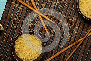 Japanese rice in a wooden bowl. Wooden chopsticks On the table of a bamboo mat. Asian cuisine. View from above.