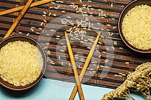 Japanese rice in a wooden bowl. Wooden chopsticks On the table of a bamboo mat. Asian cuisine. View from above.