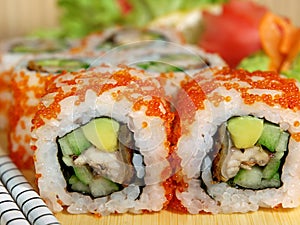 Japanese roll with eel, caviar, avocado and cucumber on a wooden tray close-up