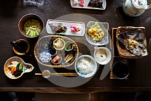 Japanese ryokan breakfast dishes including cooked white rice, grilled fish, fried egg, soup, mentaiko, pickle, seaweed, hot plate