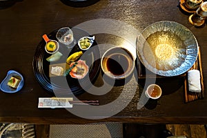 Japanese ryokan kaiseki dinner appetizer including hors d`oeuvres dishes, hot pot preparation, soy sauce bowl, liquor cup