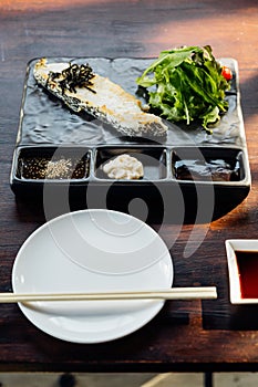 Japanese Sea Bass Fillet Steak served with salad, mayonnaise and Shoyu sauce on stone plate