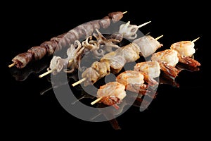 Japanese seafood kebabs. Food photo on black background with reflection.