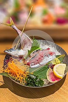 Japanese seafood sashimi cuisine of Ayu raw fish pierced on a skewer served in a metal plate.