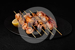 Japanese Seafood Skewers. Black tiger shrimp, scallop and salmon fillet, octopus served with lemon. Yakitori isolated on black