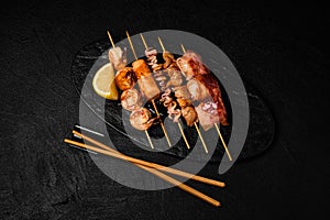 Japanese Seafood Skewers. Black tiger shrimp, scallop and salmon fillet, octopus served with lemon. Yakitori isolated on black