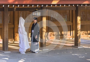 Japanese shinto wedding of a couple in kimono under a lantern of the Meiji Shrine.