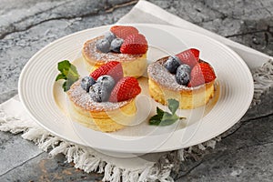 Japanese soft pancakes with strawberry and blueberries sprinkled with powdered sugar close-up on a plate. Horizontal