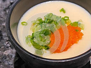 Japanese steamed egg, topping with chopped spring onion and shrimp roe serving in black bowl