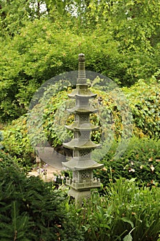 A Japanese stone lantern surrounded by dense shrubs and trees in Rotary Botanic Garden, Janesville, WI