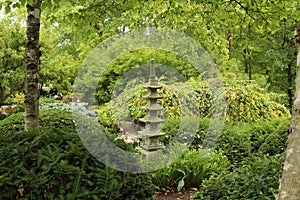 A Japanese stone lantern surrounded by dense shrubs and trees in Rotary Botanic Garden, Janesville, Wisconsin