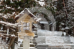 Japanese stone and wooden lantern with snow at Hida-sannogu Hie-Jinja shrine in winter season . At Gifu , Hida Takayama , Japan