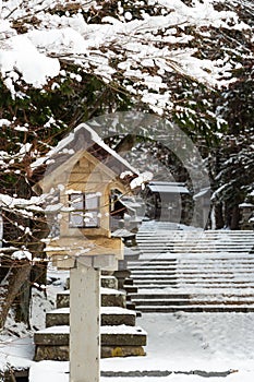 Japanese stone and wooden lantern with snow at Hida-sannogu Hie-Jinja shrine in winter season . At Gifu , Hida Takayama , Japan