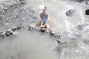 Japanese student girl damming river by stone