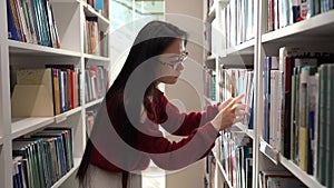 Japanese student girl look for book in university library picking novel or material for course work