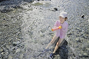 Japanese student girl playing in the river with water gun