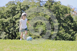Japanese student girl playing soccer on the grass