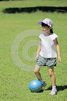 Japanese student girl playing soccer on the grass