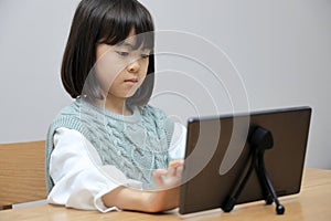 Japanese student girl using a tablet PC in dining room