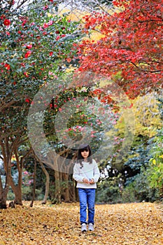 Japanese student girl walking in autumn leaves forest