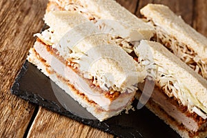 Japanese style appetizer sandwiches Katsu Sando with tonkatsu sauce and cabbage closeup on a slate board on a table. horizontal photo