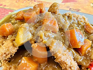 Japanese style curry, fried chicken tenders, carrots and potatoes. Close up view.