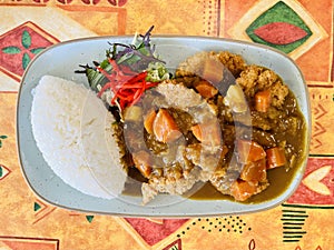 Japanese style curry, fried chicken tenders, carrots and potatoes, with rice. Top view.