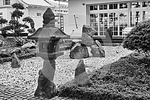 Japanese style garden behind white house with gravel, rocks and pine bushes, black and white