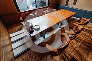 Japanese style ramen restaurant, Low table in center with seats on the ground, clothes hangers on the wall.