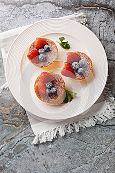 Japanese style sluffy souffle pancake dessert with blueberry and strawberry close-up on a plate. Vertical top view