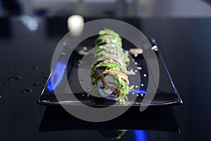 Japanese sushi on a black plate.