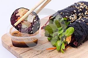 Japanese sushi with black rice and vegetable in chopsticks in ha
