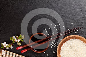 Japanese sushi chopsticks over soy sauce bowl, rice and sakura b