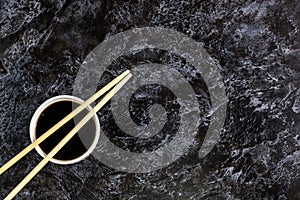 Japanese sushi chopsticks and soy sauce on black background. Top view with copyspace