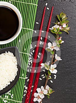 Japanese sushi chopsticks, soy sauce bowl, rice and sakura blossom