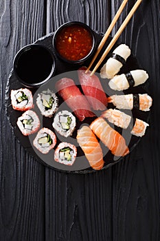 Japanese sushi food. Maki ands rolls with tuna, salmon, shrimp, crab and avocado with two sauces close-up on a slate. Vertical top