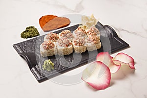 Japanese sushi roll with salmon served on plate, pink rose petals, heart shapes of spices on marble background