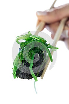 Japanese sushi roll with seaweed chukka on sticks in female hand isolated on white background. Healthy diet.