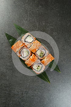 Japanese sushi roll with smoked chicken served on green tropical monstera leaf on anthracite background