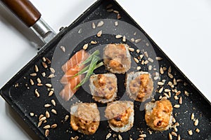 Japanese sushi rolls on a black frying pan. close view