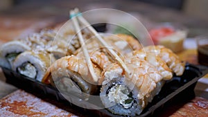 Japanese Sushi Rolls in Plastic Box a Served on Table with Bamboo Sticks, Wasabi