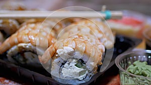 Japanese Sushi Rolls in Plastic Box a Served on Table with Bamboo Sticks, Wasabi